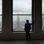 A boy looks out at the Empire State Building from the observation deck at Rockefeller Center in New York City.