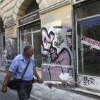 A man walks past a shuttered store in Athens, Greece: The financially strapped country is trying to secure an $11 billion bailout to avoid defaulting on its massive debt.