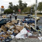 People walk past a heap of garbage in an Athens suburb: Between a trash collectors' strike and the stress of ongoing protests, Greece may be on the verge of a health crisis.