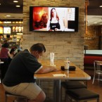 A customer sits at a table near an HDTV screen playing McDonald's new TV channel, which is being tested in California before a national rollout.