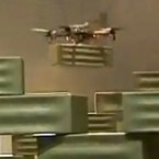 A robotic helicopter bee places a polystyrene brick onto a 20-foot tower being constructed by four robots at an exhibit in France.