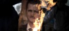 A member of Free Syrian Army burns a portrait of President Bashar al-Assad: Roughly 6,000 people have been killed during Syria's nearly-year-long uprising.