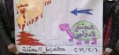Young Syrian men hold a sign depicting the international community's turtle-like pace in coming to the aid of a bleeding Syria.