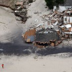 A woman walks on the beach in Mantokloking, N.J., near homes destroyed by Hurricane Sandy.