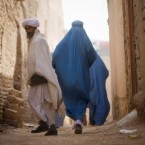 A man looks back as women walk along an alley in Herat, Afghanistan.